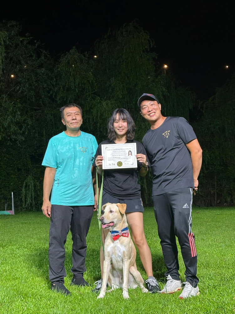 學員手持證書，與兩位導師在訓練場合照