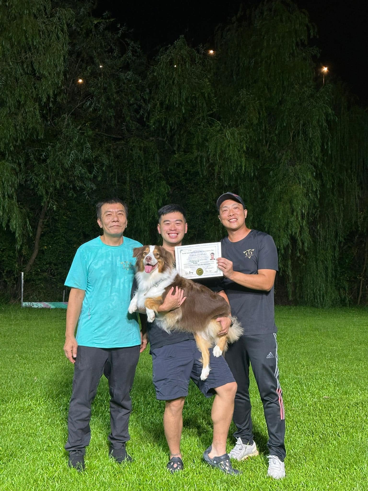 學員手持證書，與導師及兩隻狗狗在訓練場合照