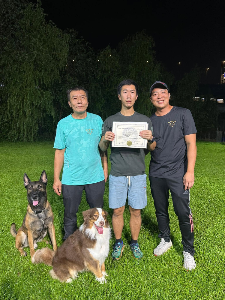 學員手持證書，與兩位導師在訓練場合照