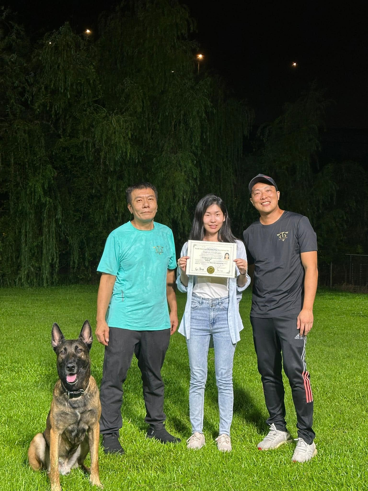 學員手持證書，與兩位導師在訓練場合照