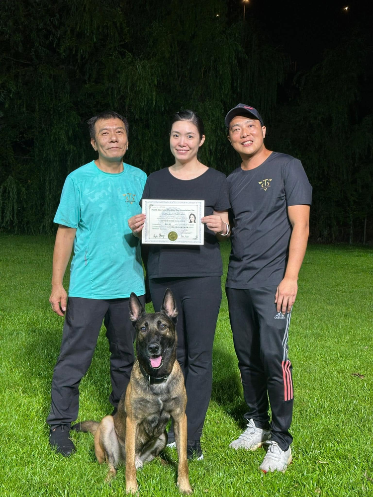 學員手持證書，與兩位導師在訓練場合照