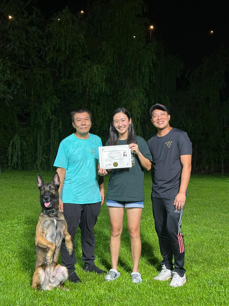 學員手持證書，與兩位導師在訓練場合照