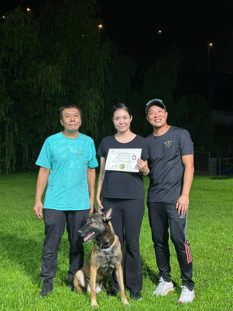 學員手持證書，與兩位導師在訓練場合照