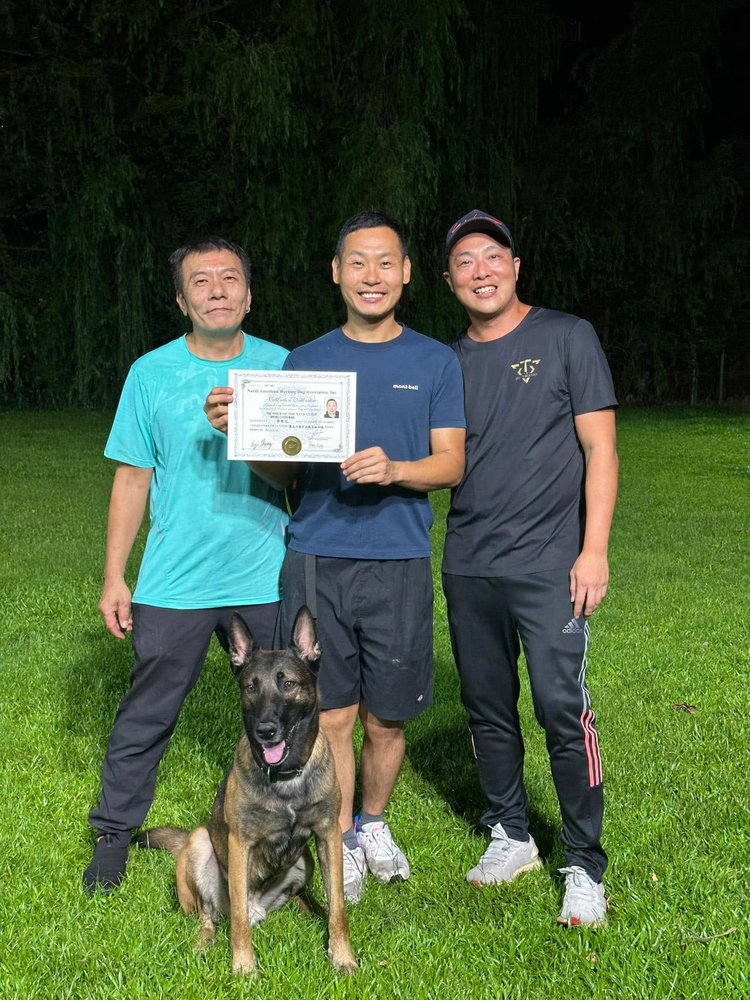 學員手持證書，與兩位導師在訓練場合照