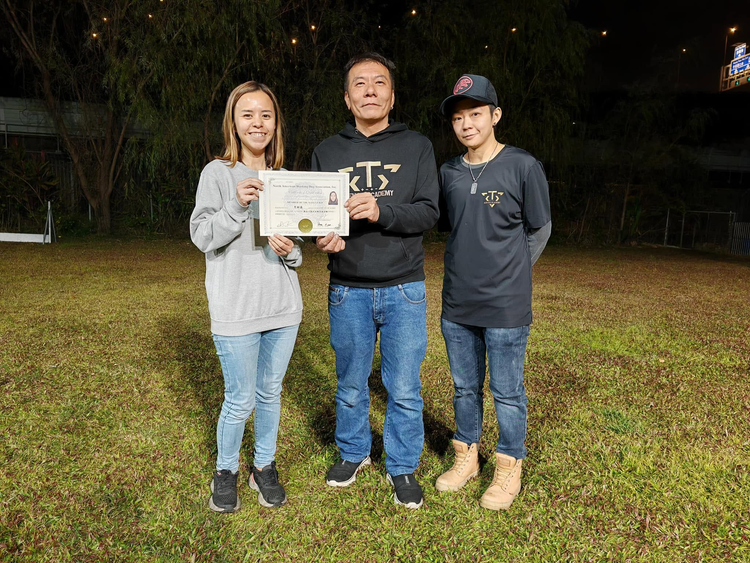 學員手持證書，與兩位導師在訓練場合照