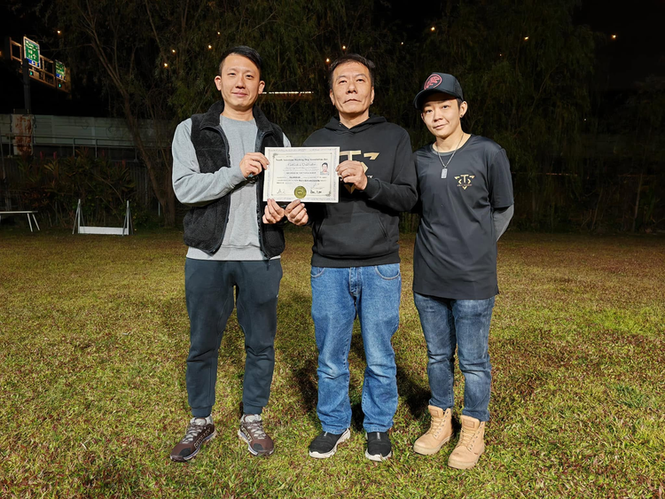 學員手持證書，與兩位導師在訓練場合照