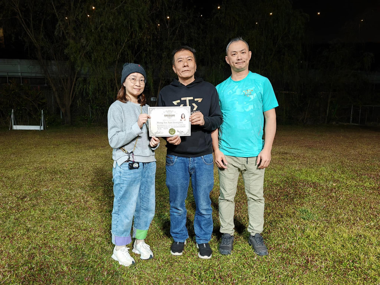 學員手持證書，與兩位導師在訓練場合照