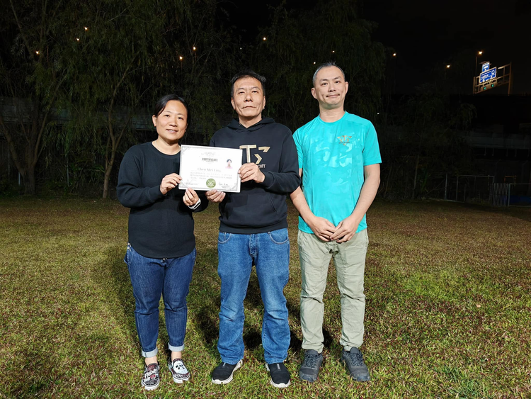 學員手持證書，與兩位導師在訓練場合照